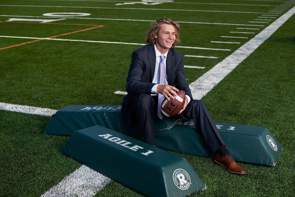 senior pictures prosper tx football player in suit at prosper high practice field