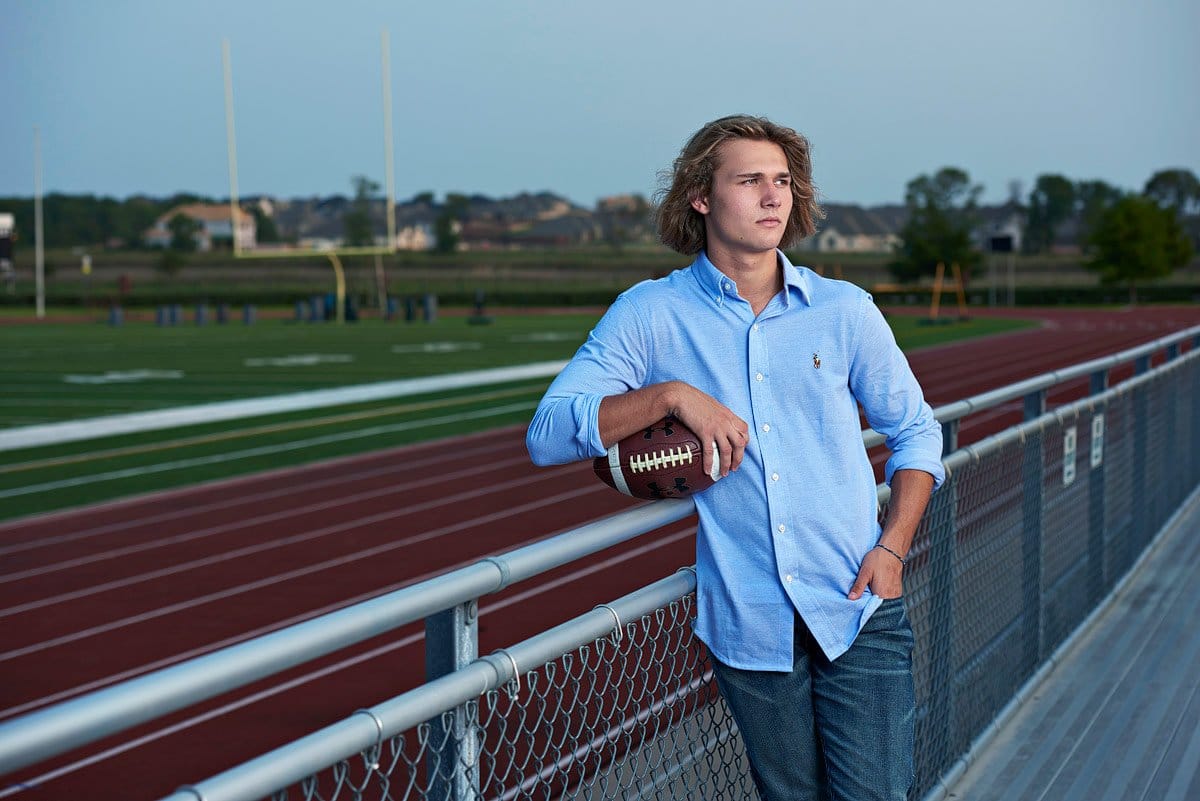 senior pictures with football at field prosper texas