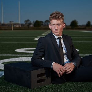 prosper boys senior pictures of football player on field in black suit