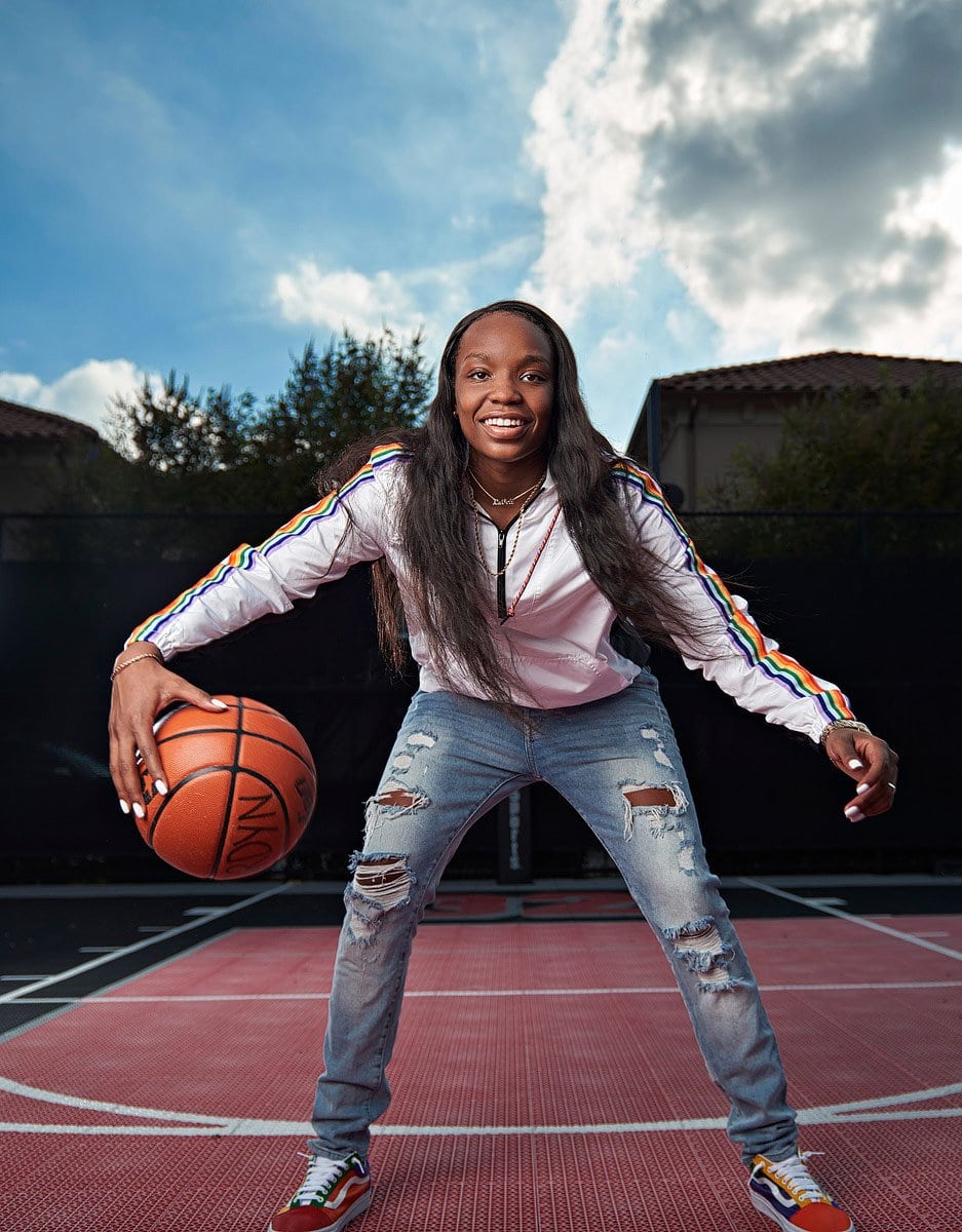 dallas high school basketball player dribbles in white jacket and jeans for senior pictures
