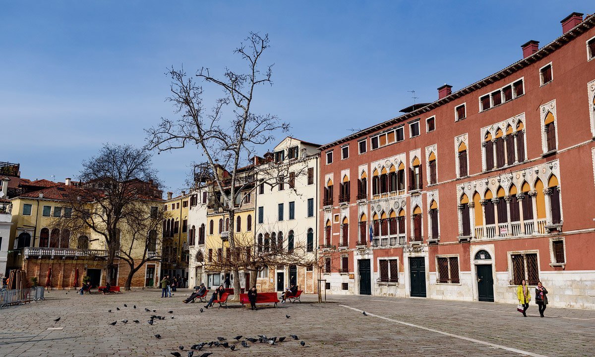 piazza in venice italy with red benches and buildings
