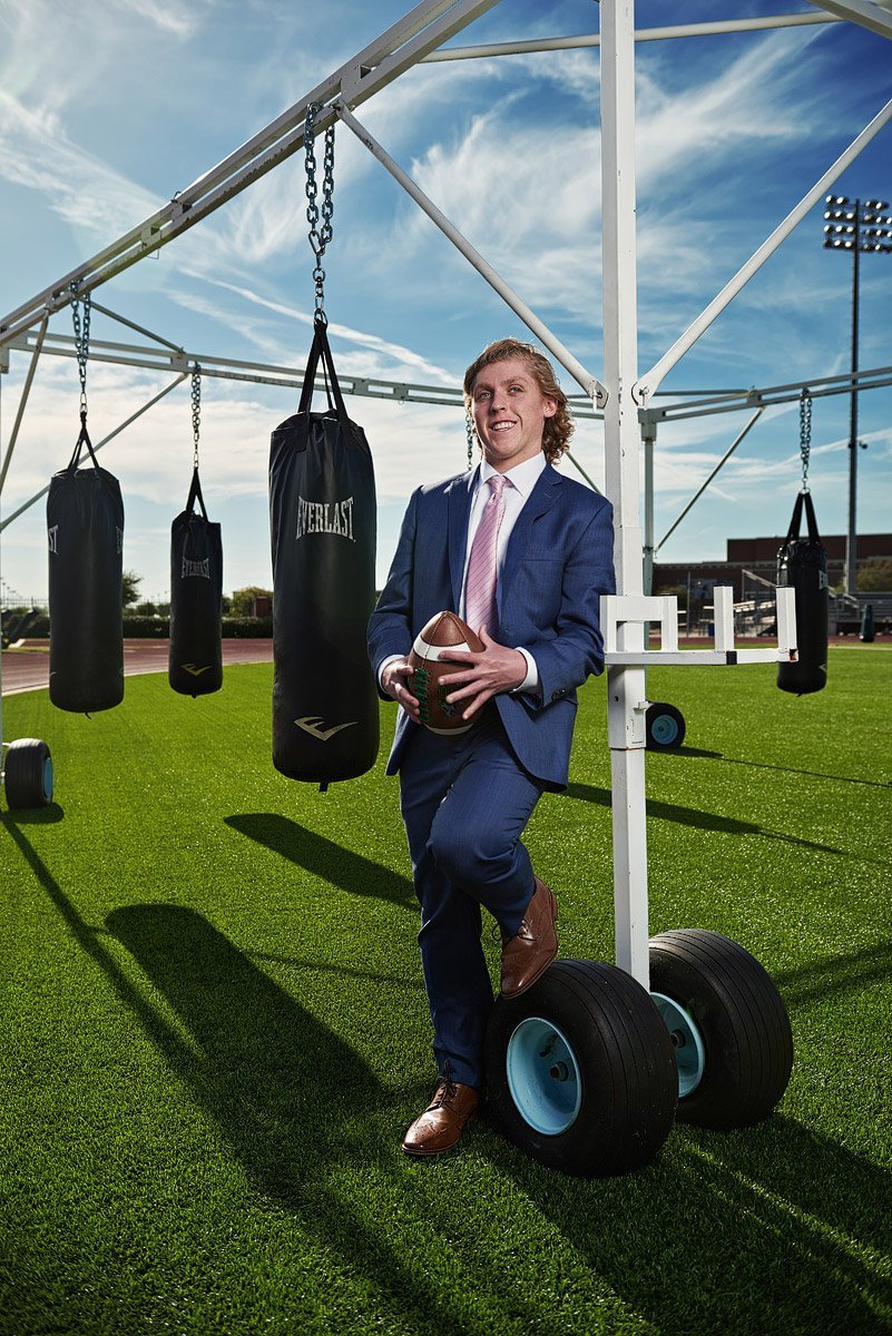 prosper senior pictures football player by punching bags on the practice field