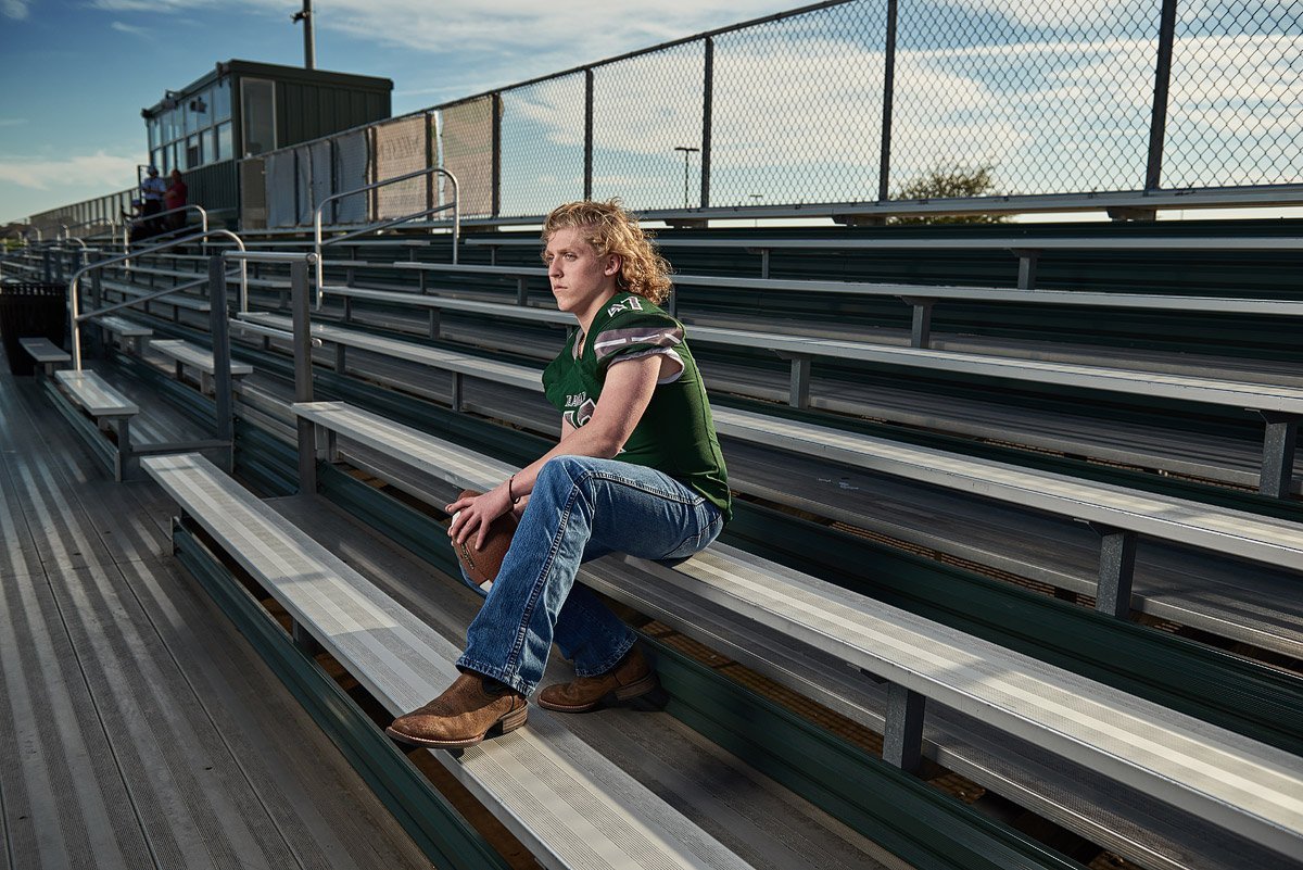 prosper senior pictures of football player in green jersey holding a football in the bleachers