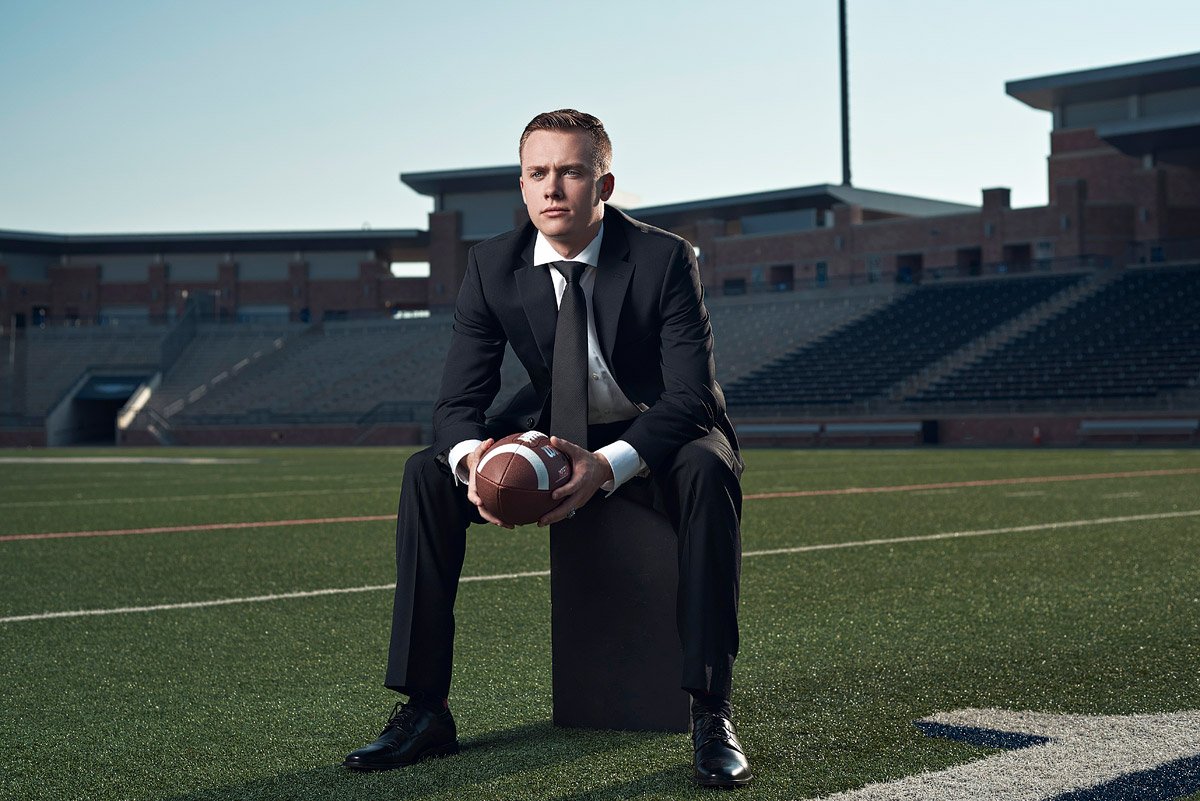 Allen senior sports portraits in a suit on the field at eagles stadium
