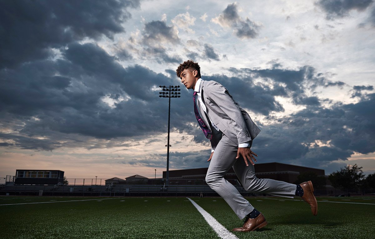 Senior Pictures in McKinney of football receiver running across field in suit