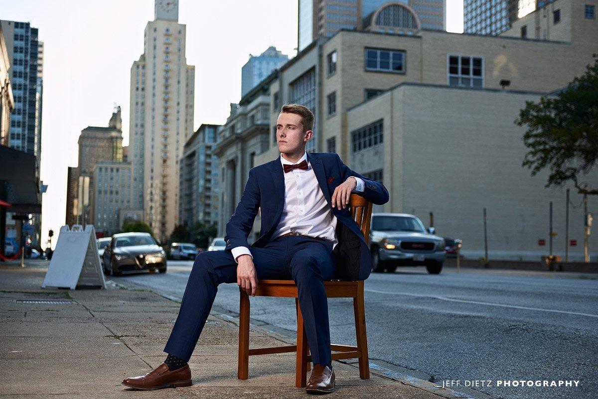 frisco liberty senior pictures in downtown dallas in a chair with suit