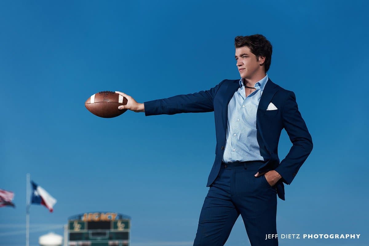 legacy Christian Senior Football player in a suit holding the football