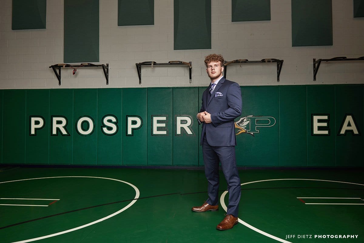 prosper wrestling room with senior rylan in a suit for senior portraits