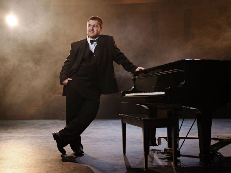 prosper senior choir member by grand piano in black suit prosper texas