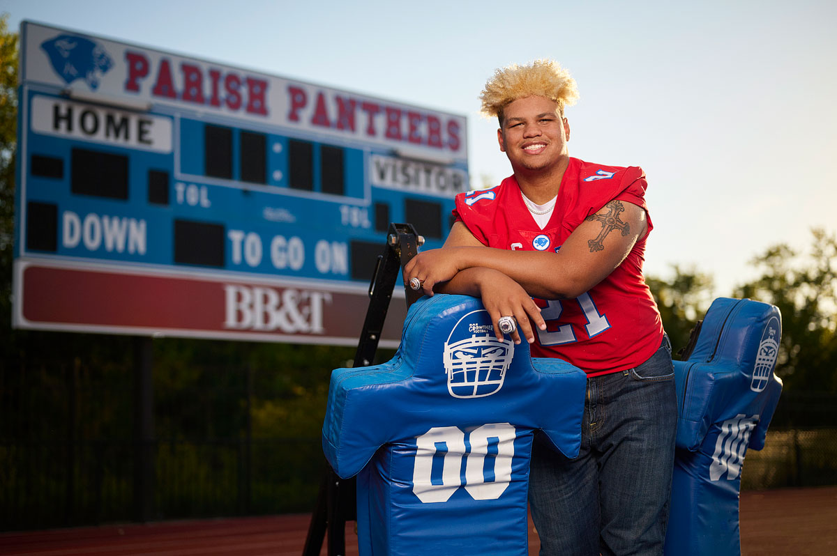 parish episcopal senior poses by score board in football jersey for senior portraits with jeff dietz photography